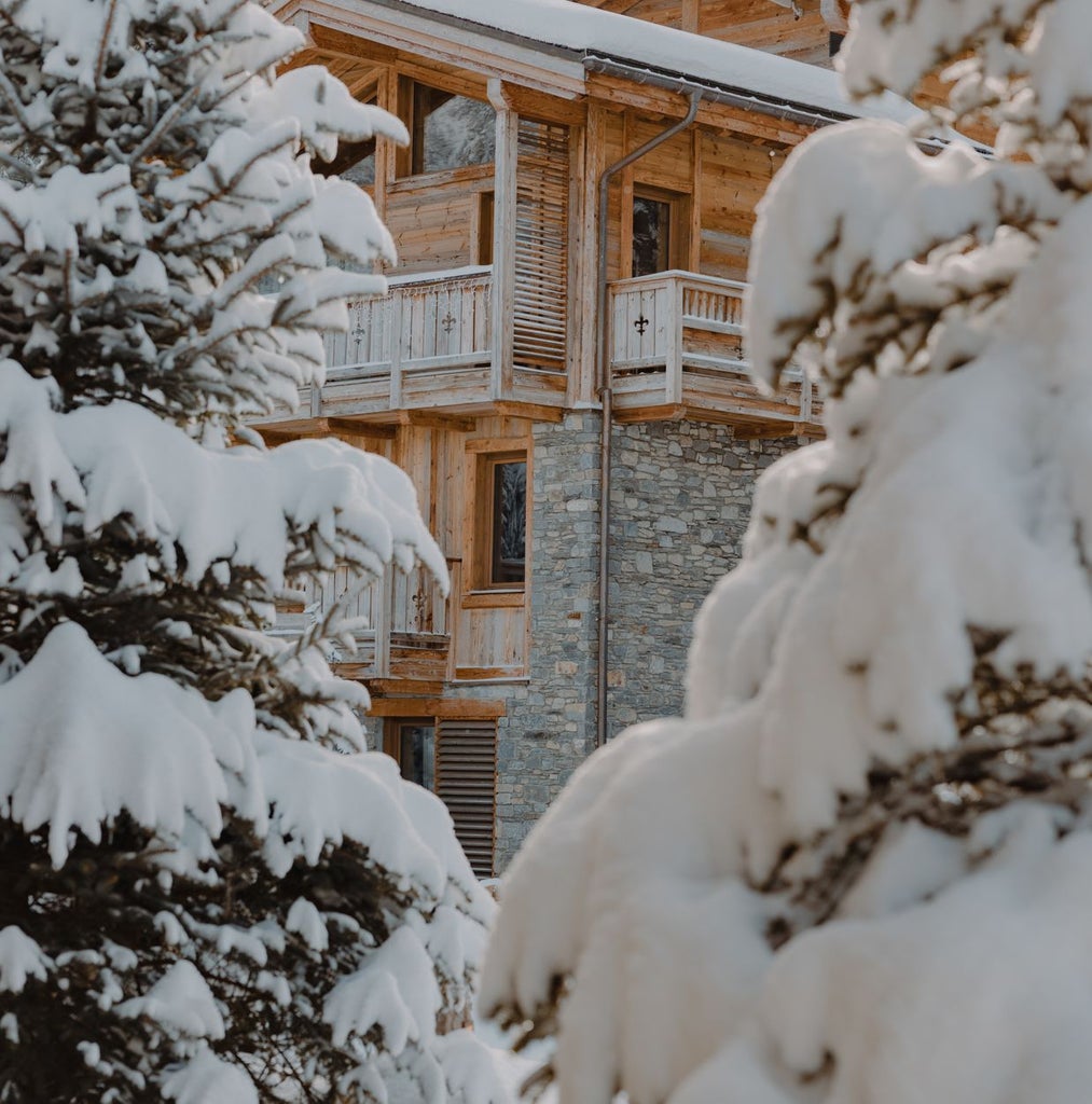 Luxurious alpine chalet-style hotel nestled in Courchevel, featuring snow-capped mountains, elegant architecture, and warm wooden exteriors with pristine winter landscape