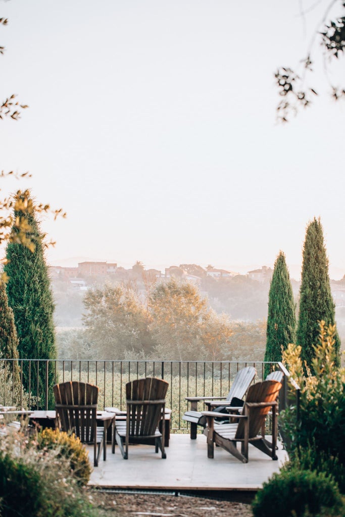 Elegant Tuscan boutique hotel with stone facade, rustic wooden shutters, and climbing vines against warm terracotta walls at sunset