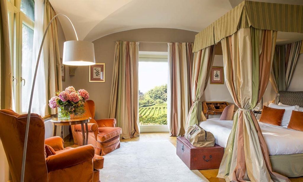 Elegant superior room at L'Albereta resort, featuring plush white bedding, contemporary furnishings, and expansive vineyard views in scenic Italian countryside