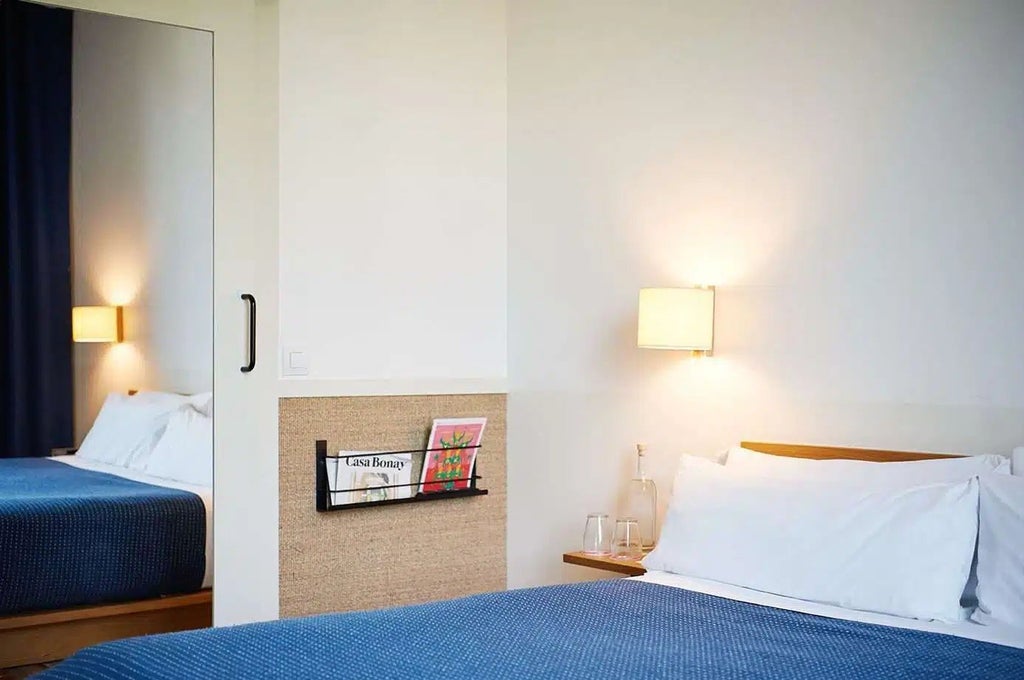 Minimalist chic hotel room with neutral tones, modern furniture, and large windows overlooking Barcelona's Gran Via, showcasing elegant urban design