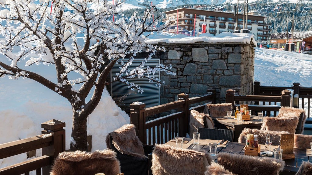 Luxury alpine chalet-style hotel nestled in snowy French mountains, featuring wooden balconies, warm lighting, and elegant winter landscape backdrop