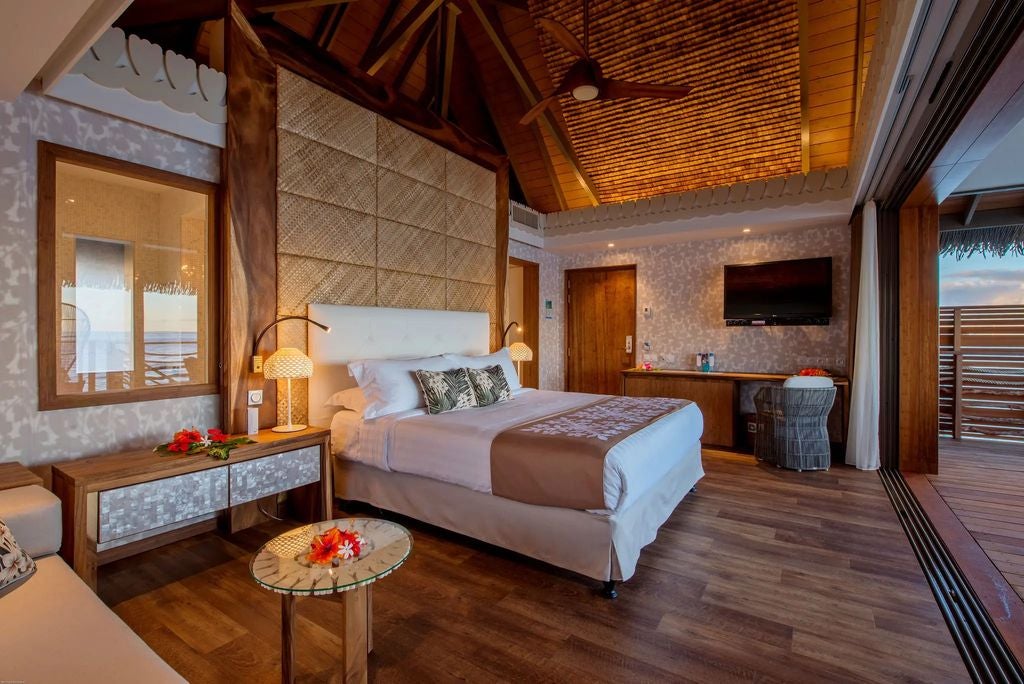 Luxurious overwater bungalow suite with private terrace, crystal-clear lagoon views, and traditional Polynesian architecture in Tahiti