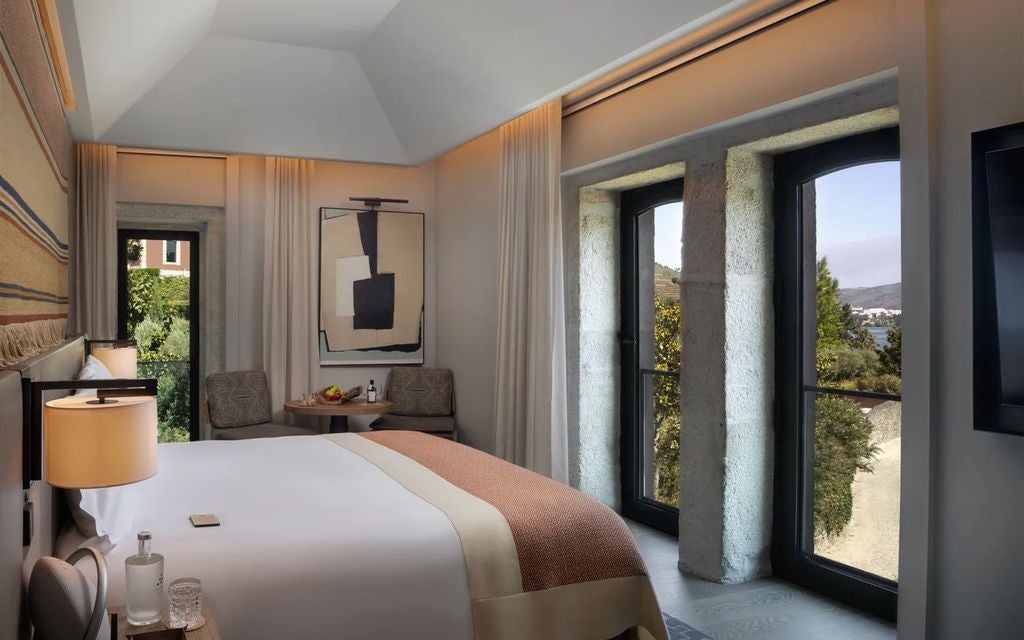 Luxurious hotel room with modern decor, floor-to-ceiling windows overlooking Douro Valley vineyards, king bed with white linens