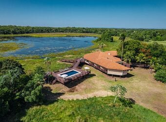 Luxurious eco-lodge nestled in Brazilian wetlands, featuring rustic wooden cabins with panoramic views of lush green landscape and wildlife habitat.