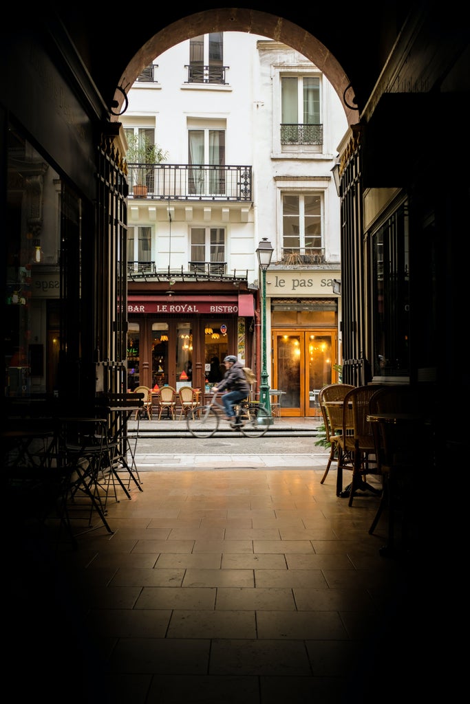 Elegant woman in designer outfit strolling past Parisian café, Eiffel Tower in soft background, golden afternoon light illuminating cobblestone street