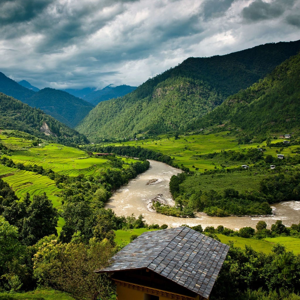 Luxurious COMO Uma Punakha hotel nestled in Bhutan's verdant valley, with traditional Bhutanese architecture framed by majestic Himalayan mountain landscape