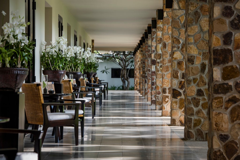 Art Deco colonial building with polished white facade, ornate archways, and manicured tropical gardens set against vibrant blue skies