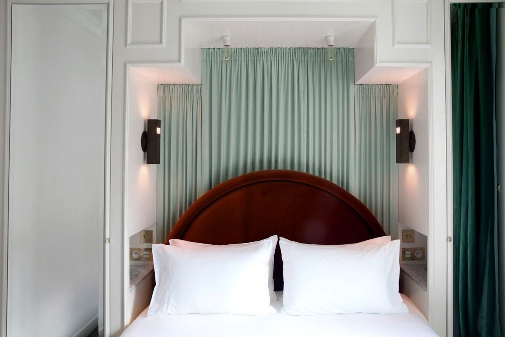 Elegant Parisian hotel room with soft neutral tones, ornate crystal chandelier, plush white bedding, and classic French architectural details