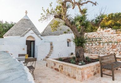 Rustic stone trulli houses of Borgo Canonica resort nestled in lush Puglia countryside, showcasing traditional white-washed architecture against golden sunlight