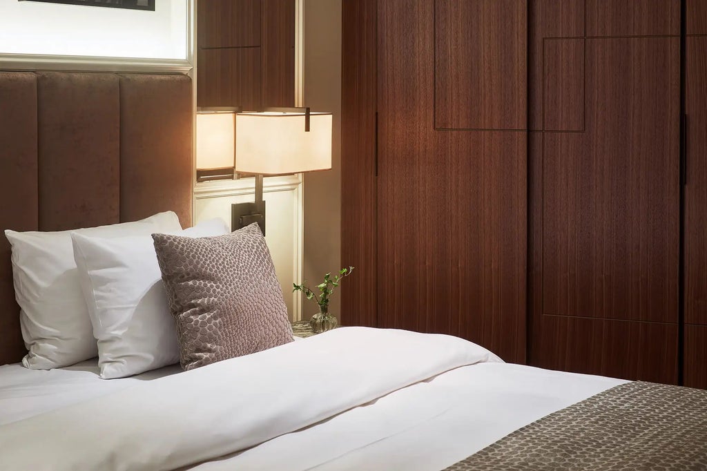 Elegant Bank Director Suite with plush king bed, sophisticated leather armchairs, rich wood paneling, and panoramic city view in Swedish luxury hotel