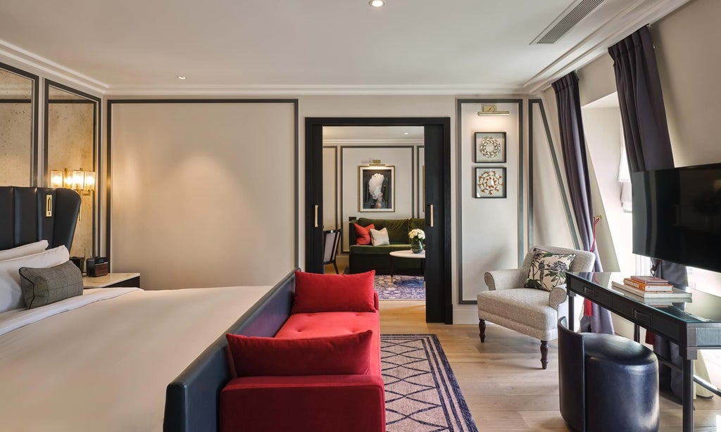 Elegant fifth-floor hotel suite with plush king bed, rich emerald green velvet chairs, and expansive city view through floor-to-ceiling windows in London's Mayfair district