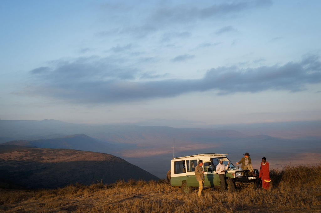 Luxurious elevated tent suite at Ngorongoro Crater's edge, featuring canvas walls, wooden deck and panoramic savanna views at sunset