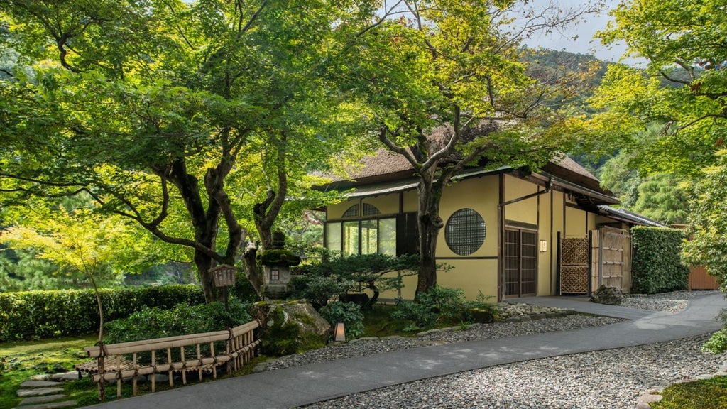 Elegant traditional Japanese ryokan-style luxury hotel nestled by tranquil Kyoto riverbank with wooden architecture and lush garden landscape