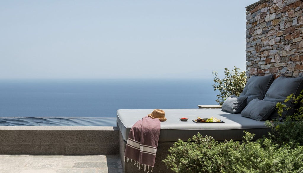 Minimalist white bedroom with blue Aegean Sea view, clean lines, elegant design, soft linens, and seamless indoor-outdoor connection in Sifnos, Greece