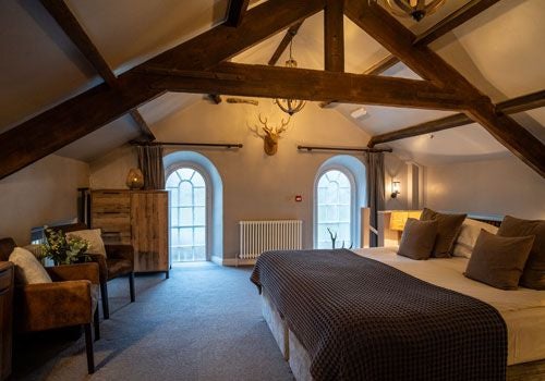 Elegant bedroom at Yorebridge House with plush white bedding, luxurious decor, classic furnishings, and soft natural light illuminating a serene UK countryside vista