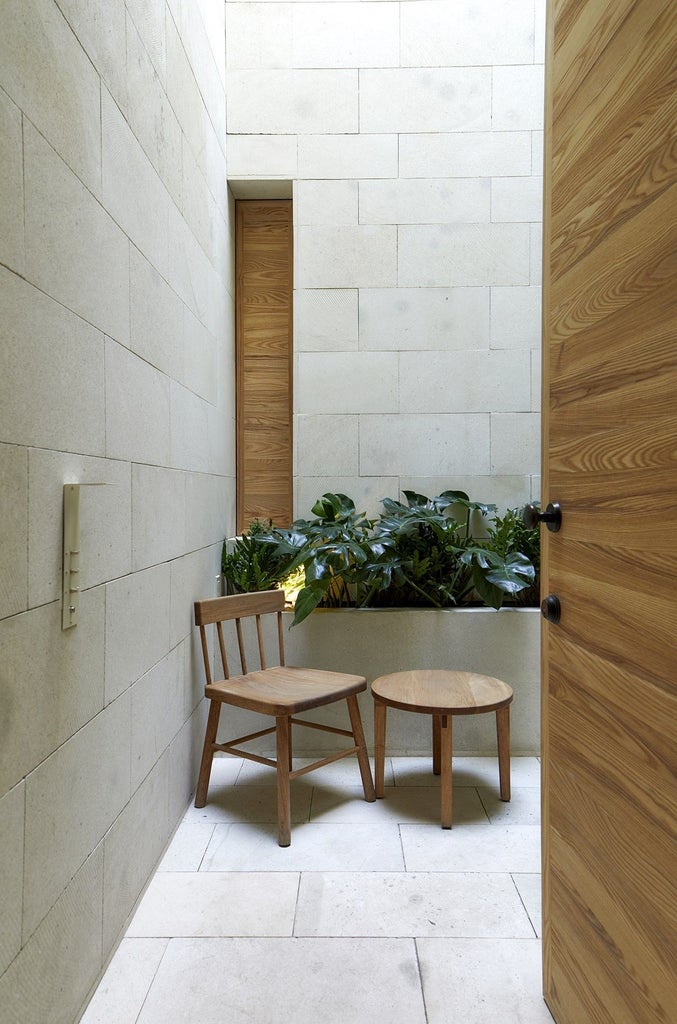 Minimalist luxury hotel room with stone walls, wood accents, and large windows offering natural light and views of Mexico City