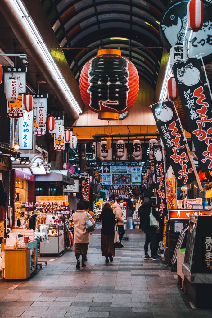 Vibrant neon signs illuminate Dotonbori district in Osaka at night, with iconic Glico running man sign reflecting in canal waters below