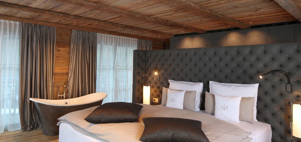 Luxurious Alpine chalet bedroom with panoramic mountain views, elegant wood paneling, plush white bedding, and modern minimalist design in Austria.