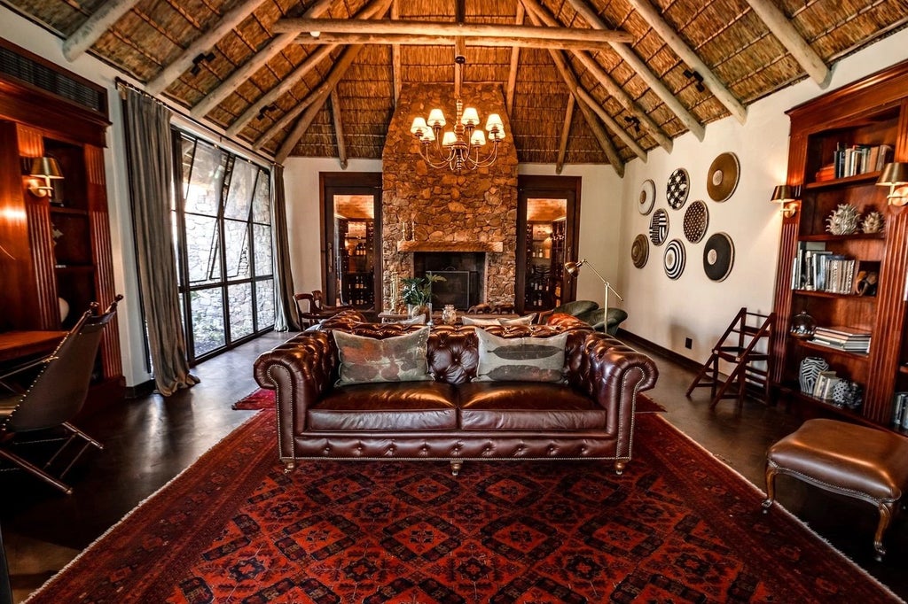 Elegant open-air safari lodge with infinity pool overlooking African savanna, thatched roof pavilion and natural stone accents