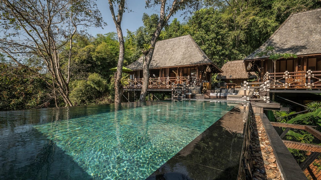 Luxurious safari-style tented suite overlooking lush jungle canopy with private wooden deck and elegant outdoor furniture in Thailand