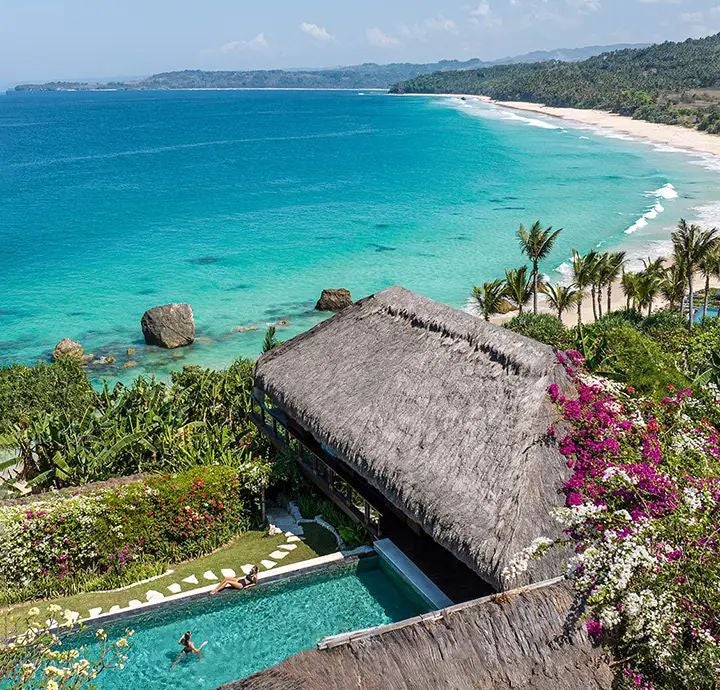 Luxurious beachfront villa at NIHI Sumba with seamless indoor-outdoor design, wooden deck, tropical landscape, and panoramic ocean views in Indonesia