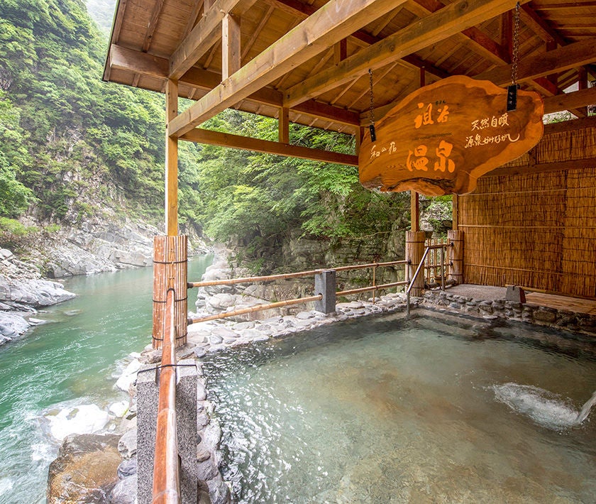 Luxury mountain-view onsen bath overlooks misty valley in Tokushima, with private cedar-lined outdoor hot springs and safety railings