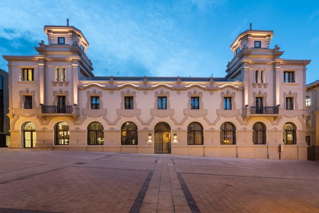 Elegant historic postal office turned luxury hotel in Spain with ornate stone facade, arched windows and grand architectural details