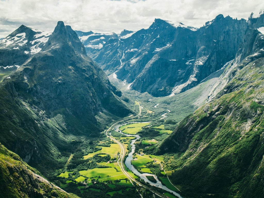 Panoramic mountain vista with sweeping fjord views, rugged Nordic landscape, luxurious wooden viewing platform against dramatic scenset scenery in Norway