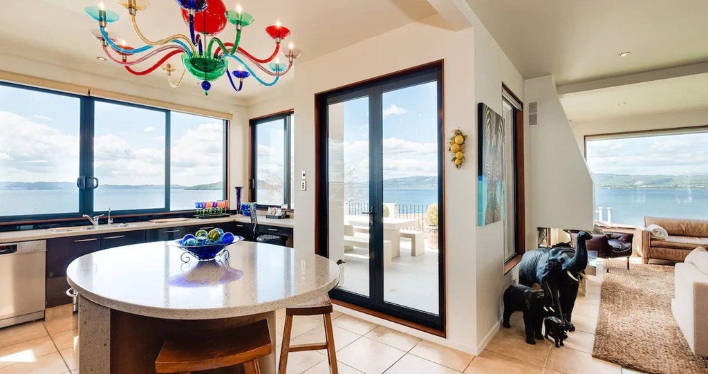 Luxurious 4-bedroom villa with panoramic water views, modern coastal decor, expansive windows, and elegant open-plan living space overlooking scenic New Zealand landscape