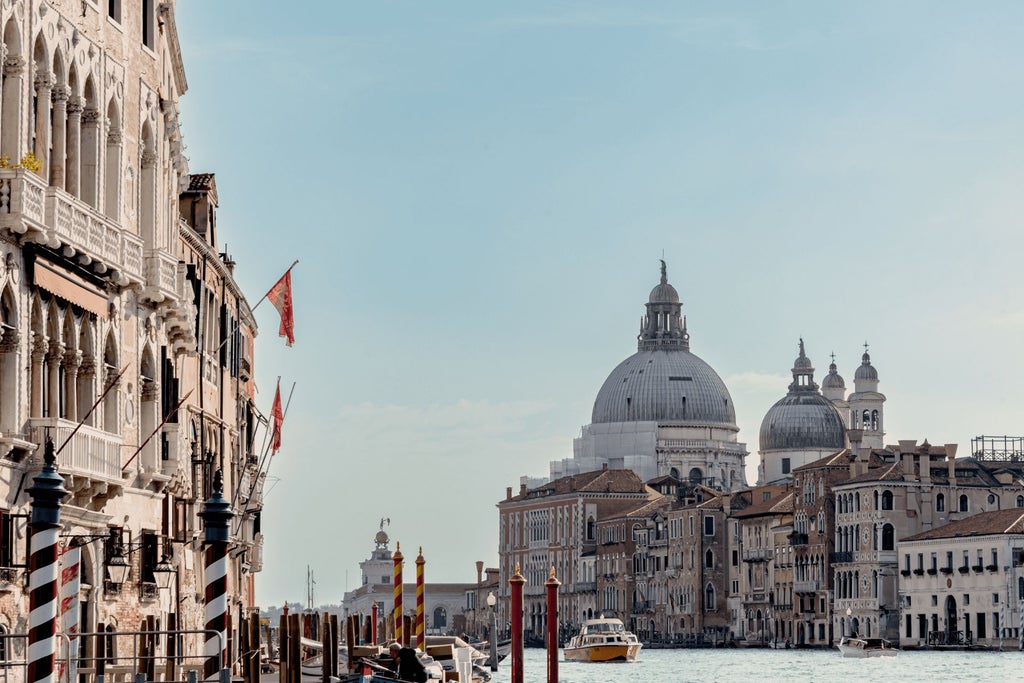 Elegant Venetian palazzo hotel with ornate marble facade, historic architecture, and warm golden lighting reflecting on canal waters at dusk