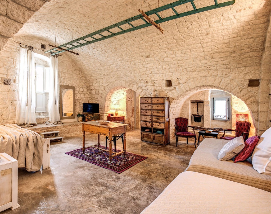 Rustic stone-walled Junior Suite at Masseria Cervarolo, featuring traditional Italian design with elegant white linens and subtle natural lighting