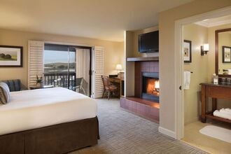 Spacious coastal suite with ocean-inspired decor, wooden floors, king bed, and panoramic windows overlooking Bodega Bay's serene landscape