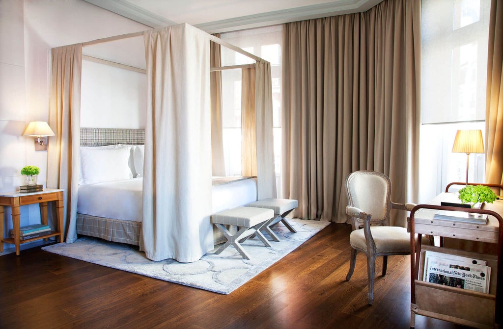 Elegant junior suite at luxurious URSO Hotel & Spa in Madrid, featuring plush bedding, warm neutrals, and panoramic palace view through large windows