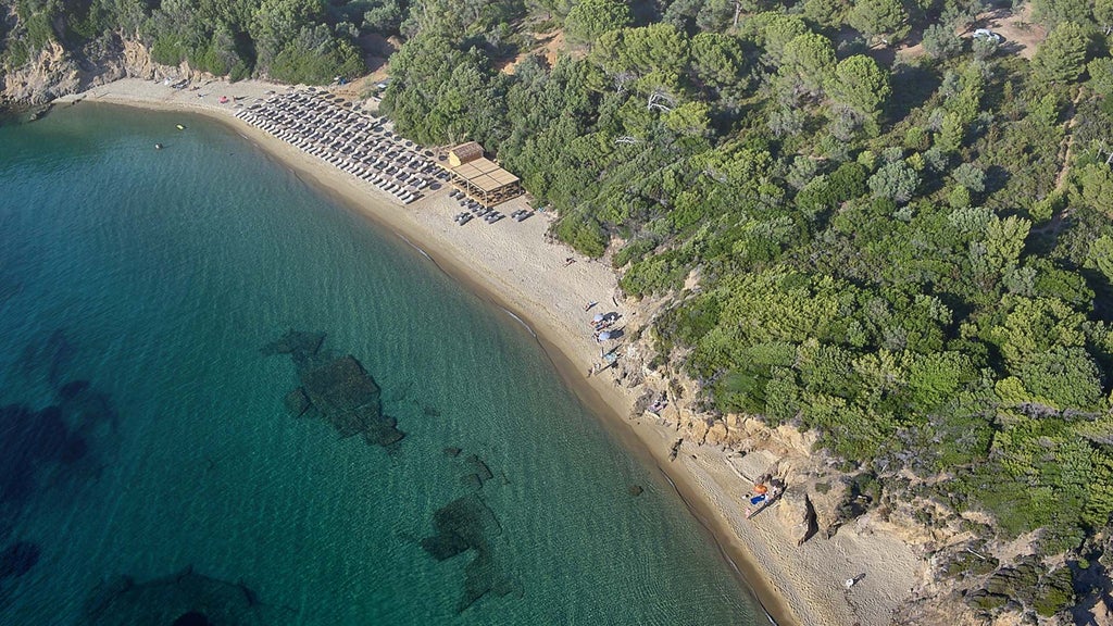 Luxurious beachfront hotel with white minimalist architecture, nestled among lush greenery overlooking the turquoise Aegean Sea in Skiathos, Greece