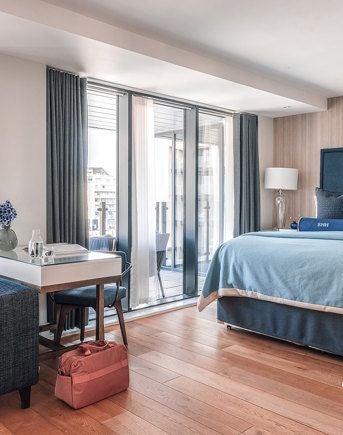 Spacious double room with elegant Juliet balcony overlooking Southampton's harbour, featuring contemporary design and plush bedding in neutral tones