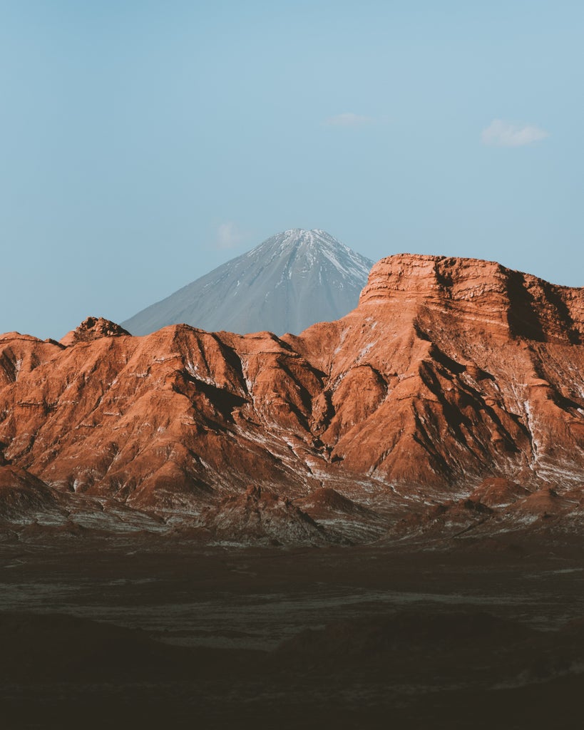 Towering sand dunes at sunset in Chile's Atacama Desert, glowing orange-red against a deep blue sky with scattered wispy clouds