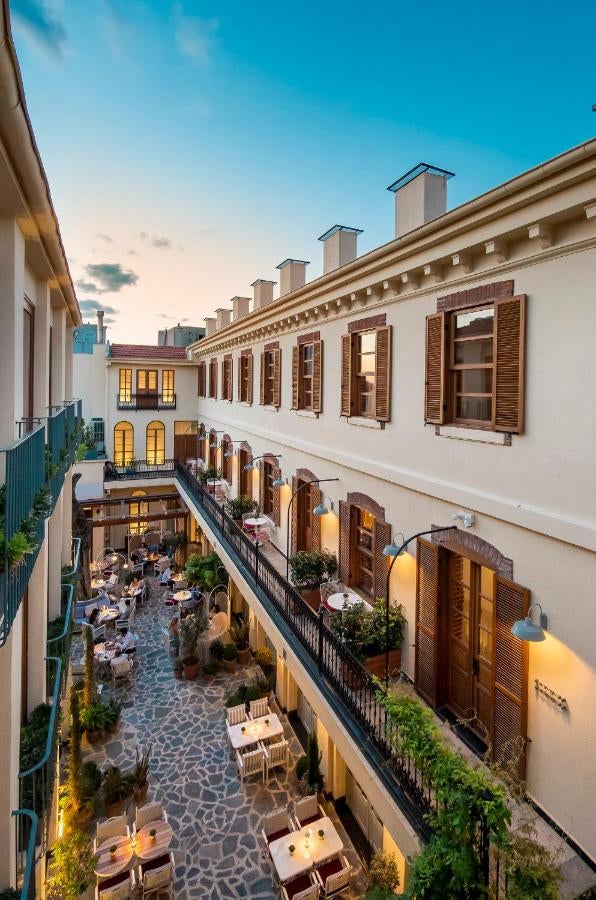 Elegant stone hotel converted from historic schoolhouse features arched windows, wrought-iron balconies and flowering Mediterranean garden