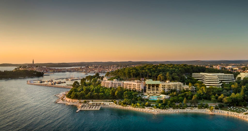 Elegant 5-star seaside hotel with stone facade, palm trees and infinity pool overlooking the crystal blue Adriatic Sea in Rovinj