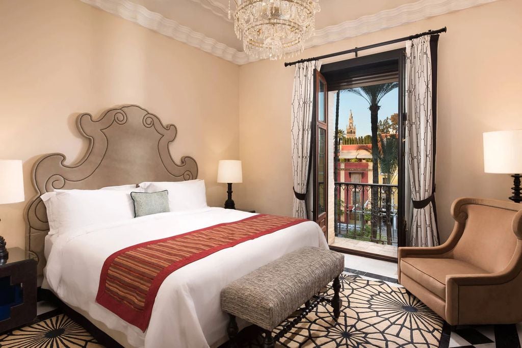 Ornate Moorish-style archways and decorative tiles adorn the exterior courtyard of Hotel Alfonso XIII, with elegant palm trees and fountains