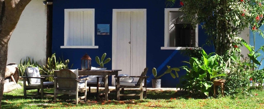 Luxury eco-chic boutique hotel nestled in lush tropical landscape, featuring rustic wooden architecture and vibrant greenery in Trancoso, Brazil.