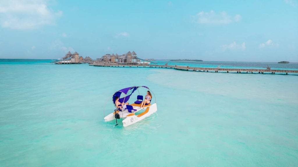 Multi-level luxury treehouse villa with wooden walkways, surrounded by lush tropical forest and turquoise Maldivian waters below