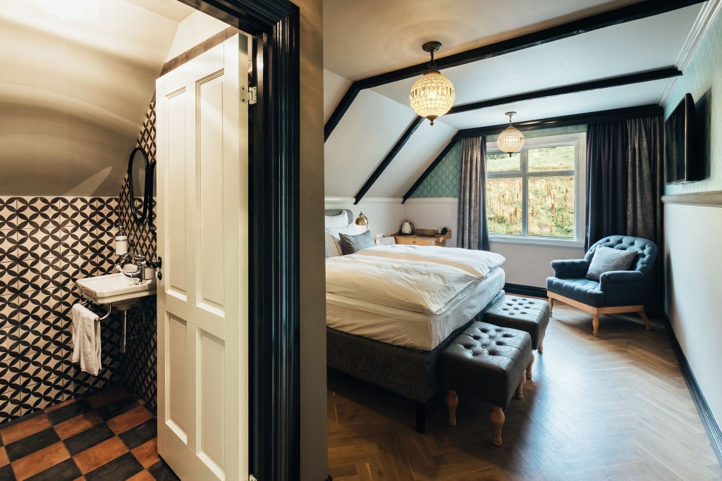 Elegant wooden-paneled single hotel room with minimalist Nordic design, warm neutral tones, and large window overlooking scenic Icelandic landscape