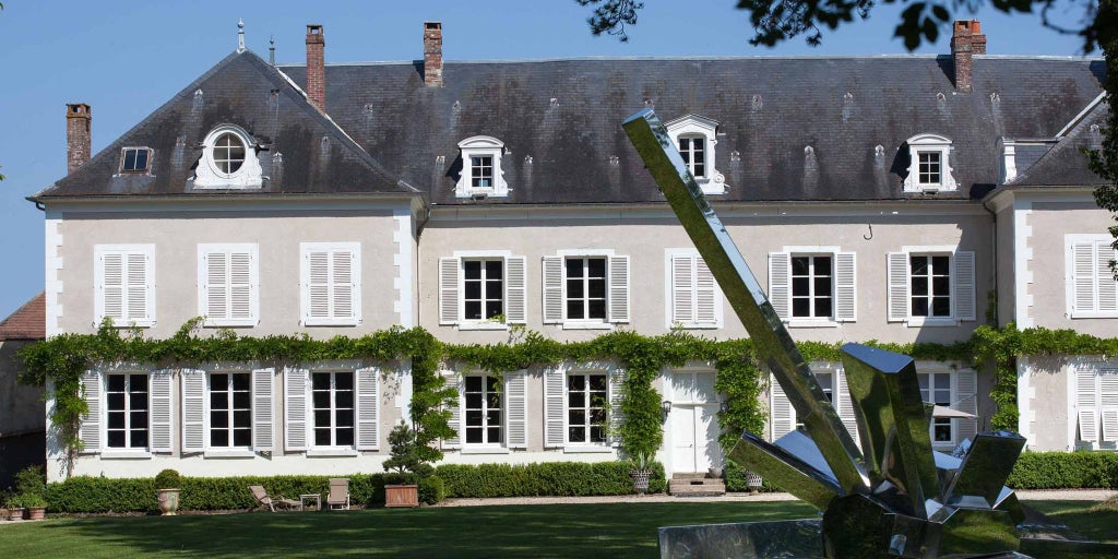 Luxurious stone château with elegant French architectural details, manicured gardens, and soft evening light casting a warm glow on the historic property's facade