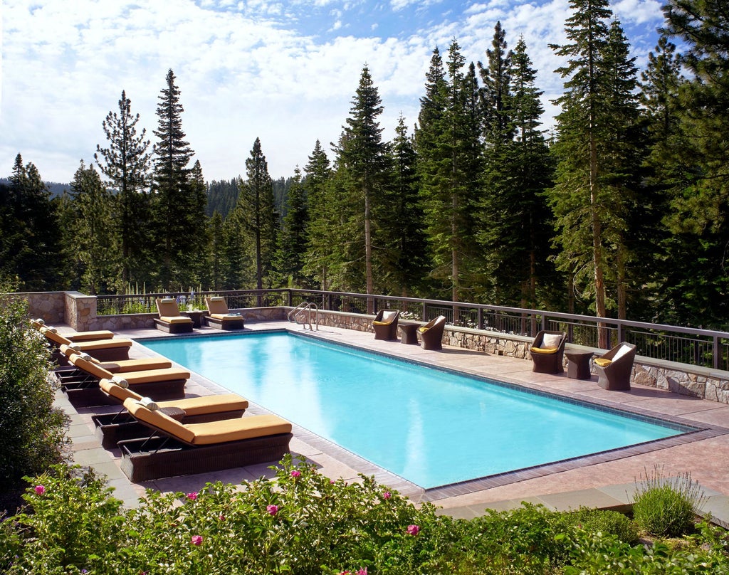 Elegant stone and timber Ritz Carlton resort nestled in snowy pine forest, with mountain views and outdoor fire pits at dusk