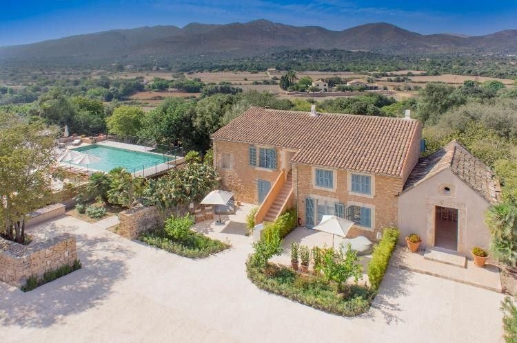 Elegant stone villa with rustic Mediterranean architecture nestled among manicured gardens, featuring a tranquil swimming pool and mountain views