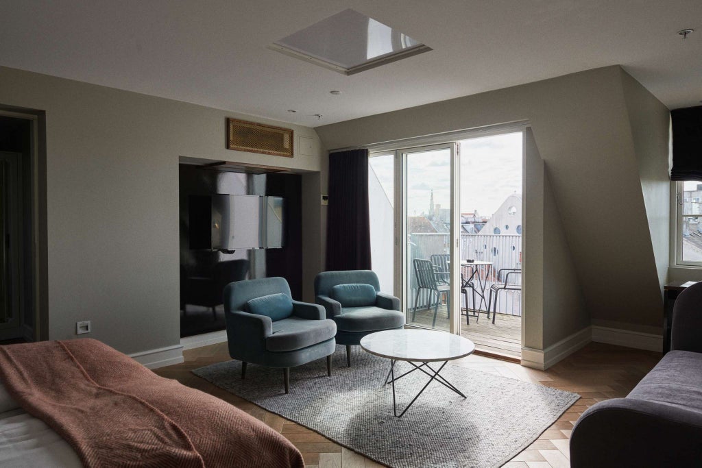 Luxurious penthouse suite in Hotel Skt. Annæ with modern minimalist decor, expansive windows revealing scenic Danish cityscape and elegant furnishings