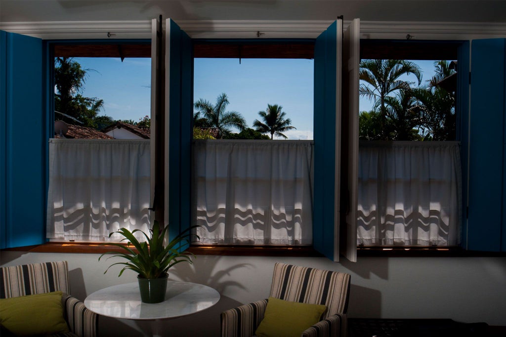 Elegant green-themed luxury suite with white linens, turquoise accents, wooden floor, and plush furnishings at boutique Brazilian hotel Casa Turquesa