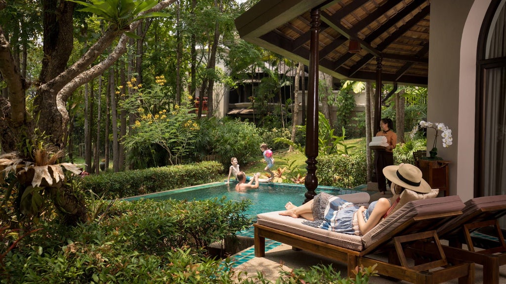 Luxurious infinity pool overlooking lush green rice terraces at sunset, with traditional Thai-style pavilions and mountain views beyond