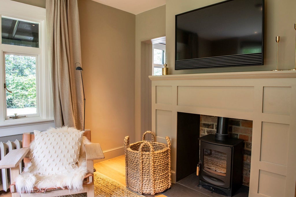 Luxurious rustic church lodge bedroom with soft neutral tones, wooden floors, elegant four-poster bed, and large windows overlooking countryside scenery at Heckfield Place