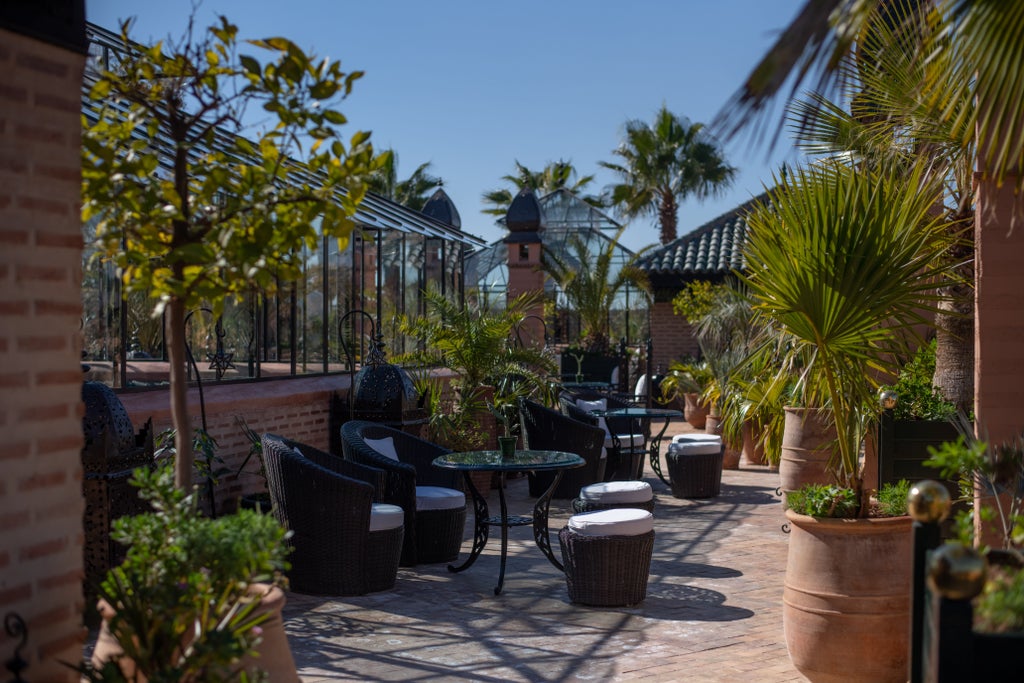 Ornate Moroccan courtyard with intricate archways, marble fountain, and lush potted plants at luxury La Sultana riad in Marrakech